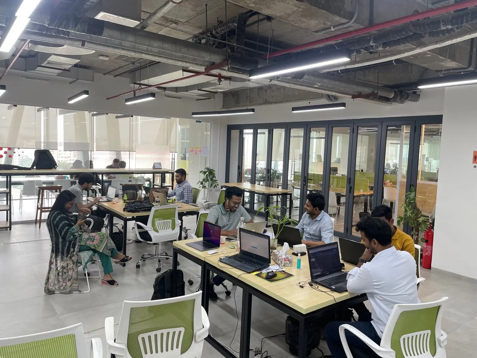 Cloud Production developers working at their desks in the company's open-plan office, under an exposed ceiling with fluorescent lighting