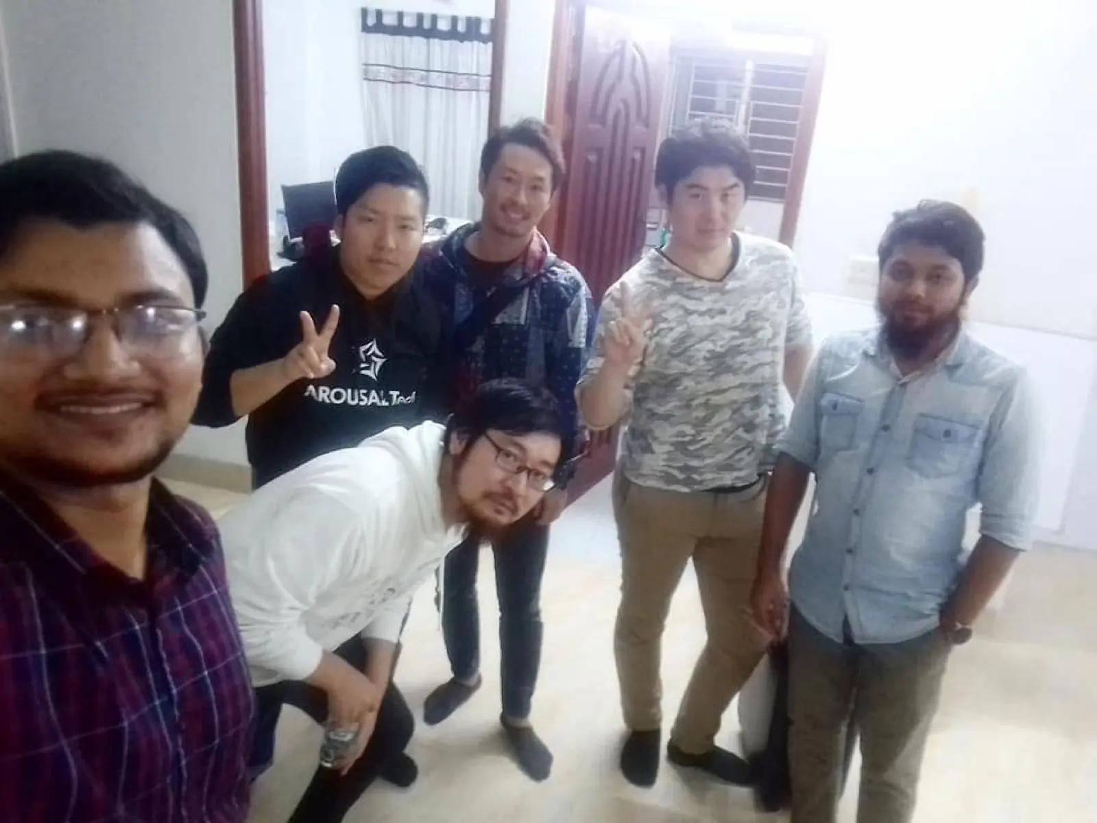 Six colleagues posing together in a relaxed group, three of them Japanese collaborators